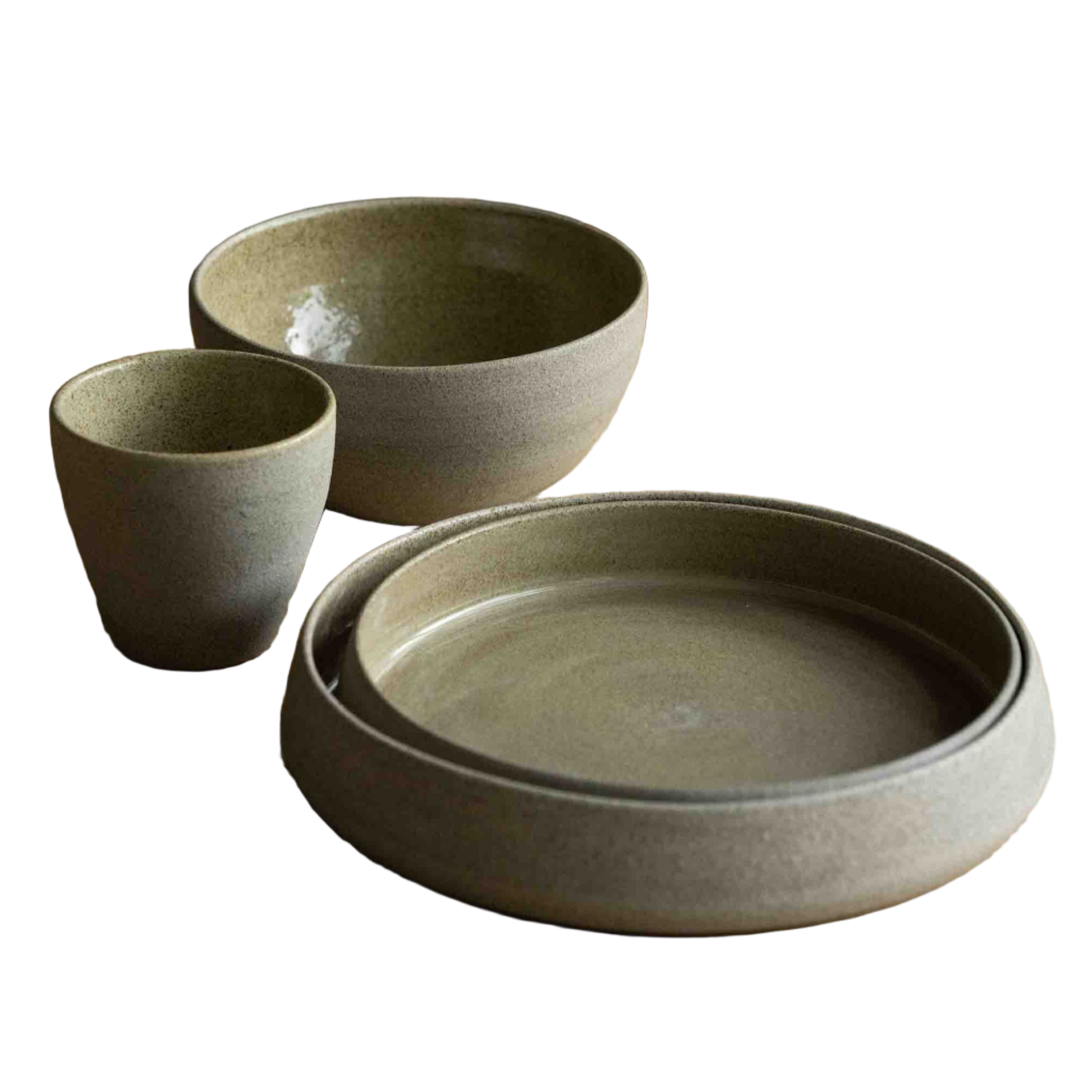 Set of ceramic bowls and a plate on a wooden table with a chair in the background.